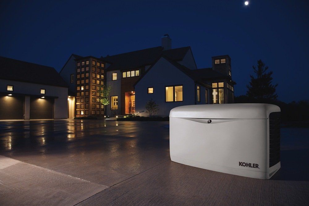 A kohler generator is sitting in front of a house at night
