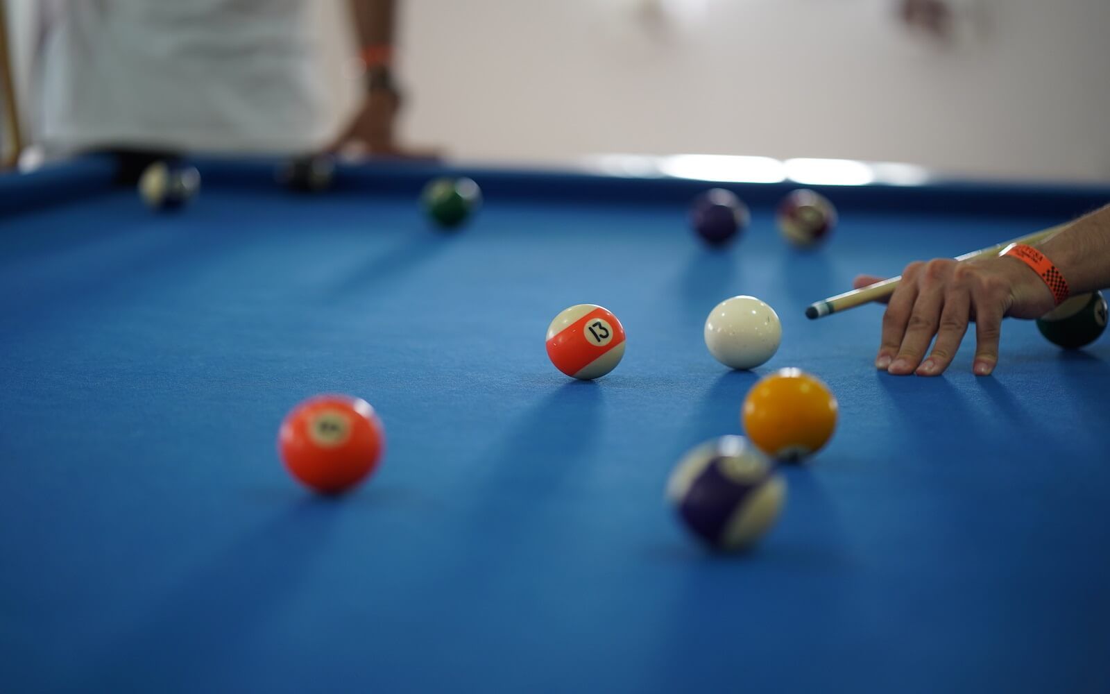 Eine Person spielt Billard auf einem blauen Billardtisch.