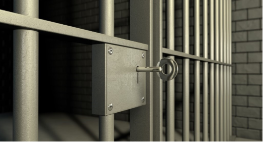 Close-up of jail cell bars and door, with a key in the lock, hinting at the possibility of escape.