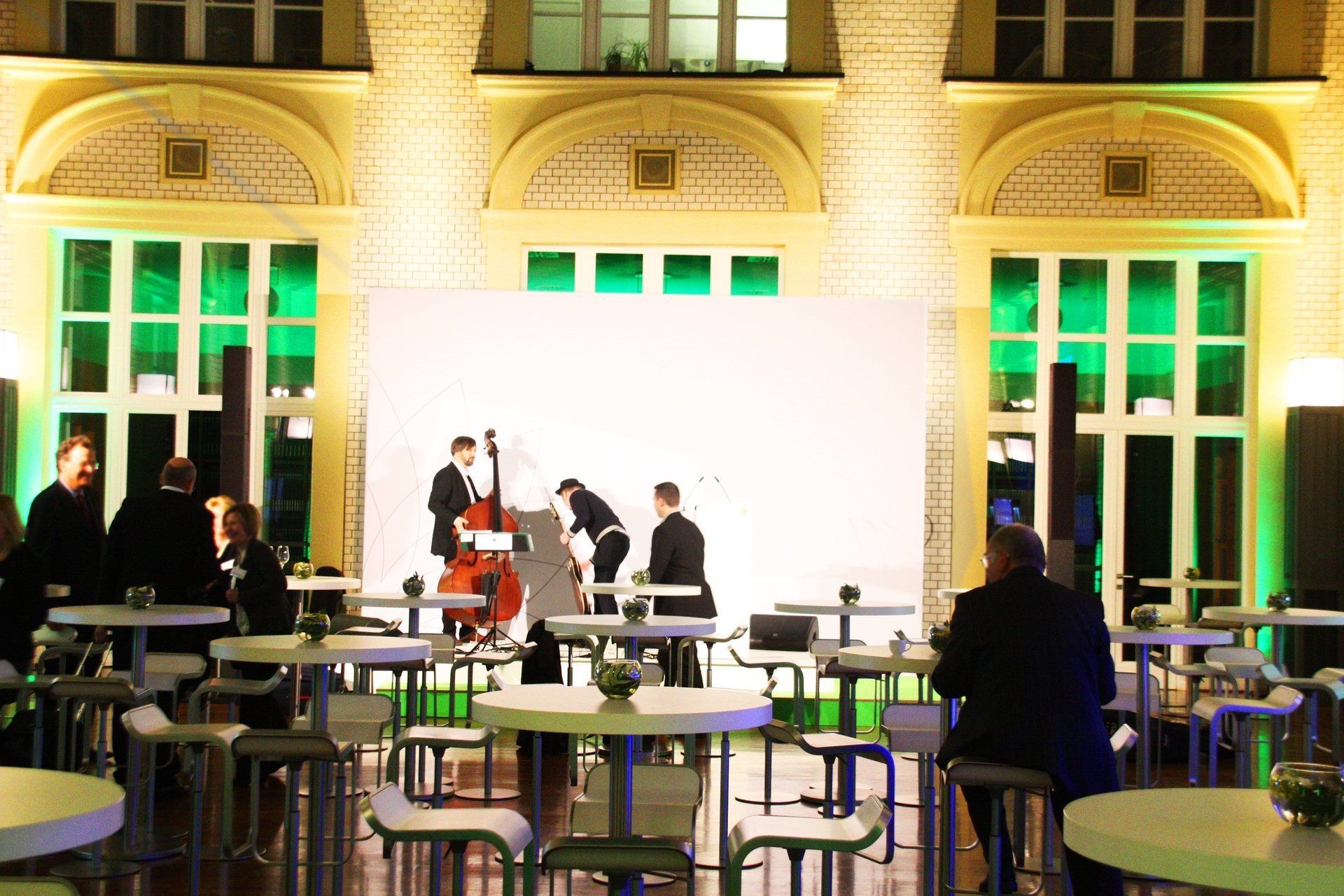 Runde Tische mit Barhockern im Lichthof des F.A.Z. Atriums. Im hintergrund ein Streich-Trio