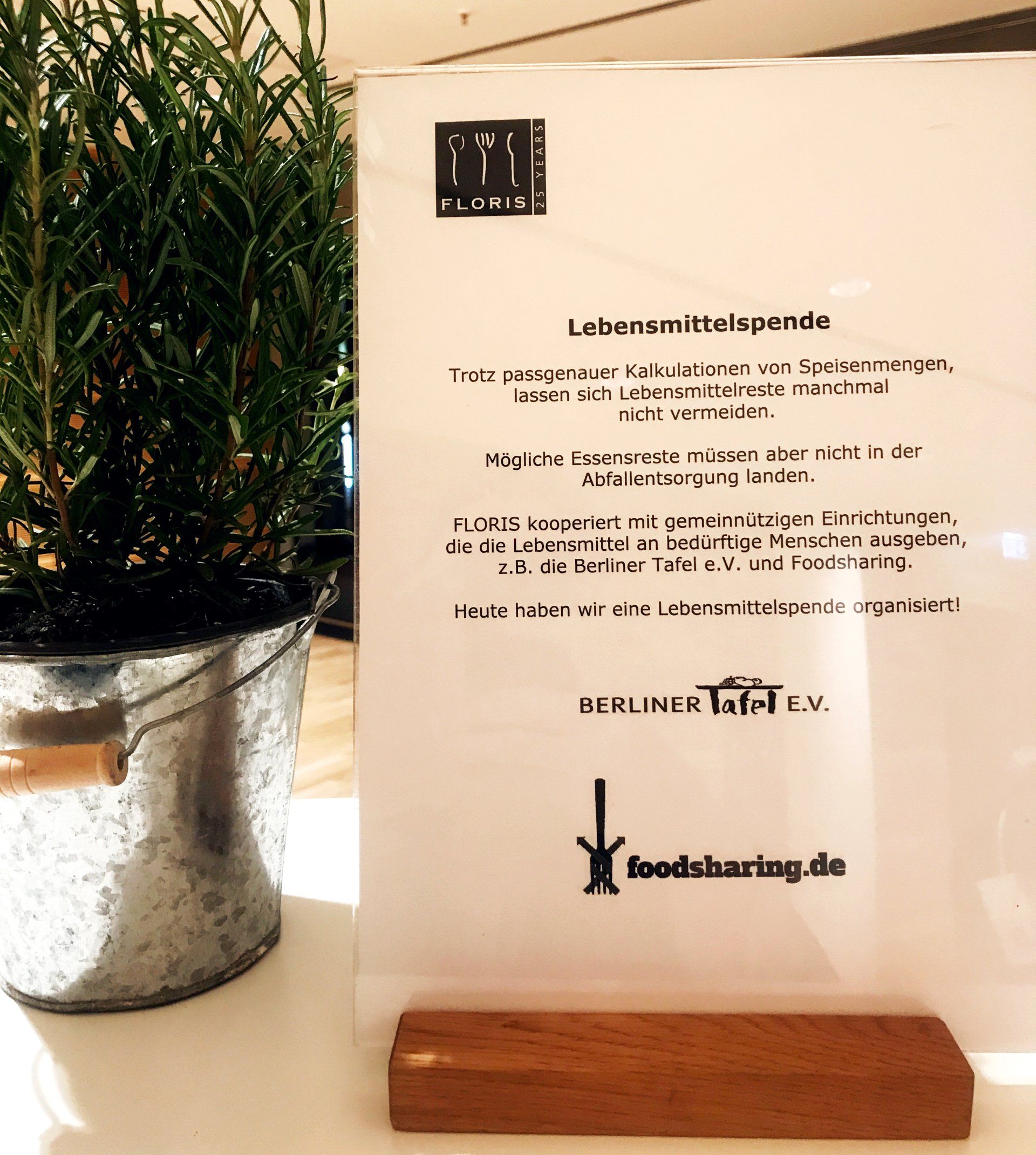 FLORIS Catering Aufsteller Lebensmittelspende neben Kräutertopf mit Rosmarin