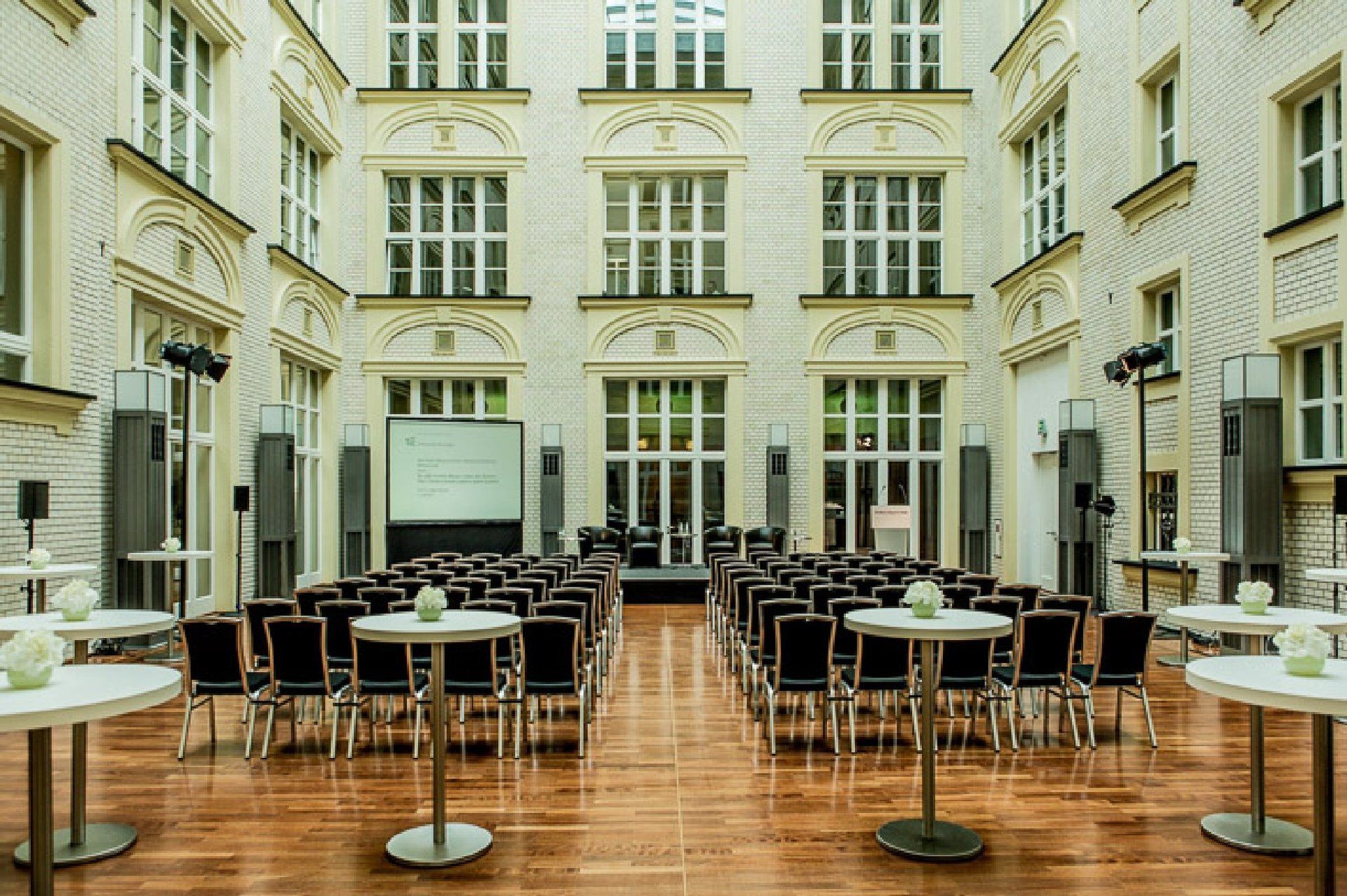 Stuhlreihen und Bühne im Lichthof, im Vordergrund dekorierte Stehtische