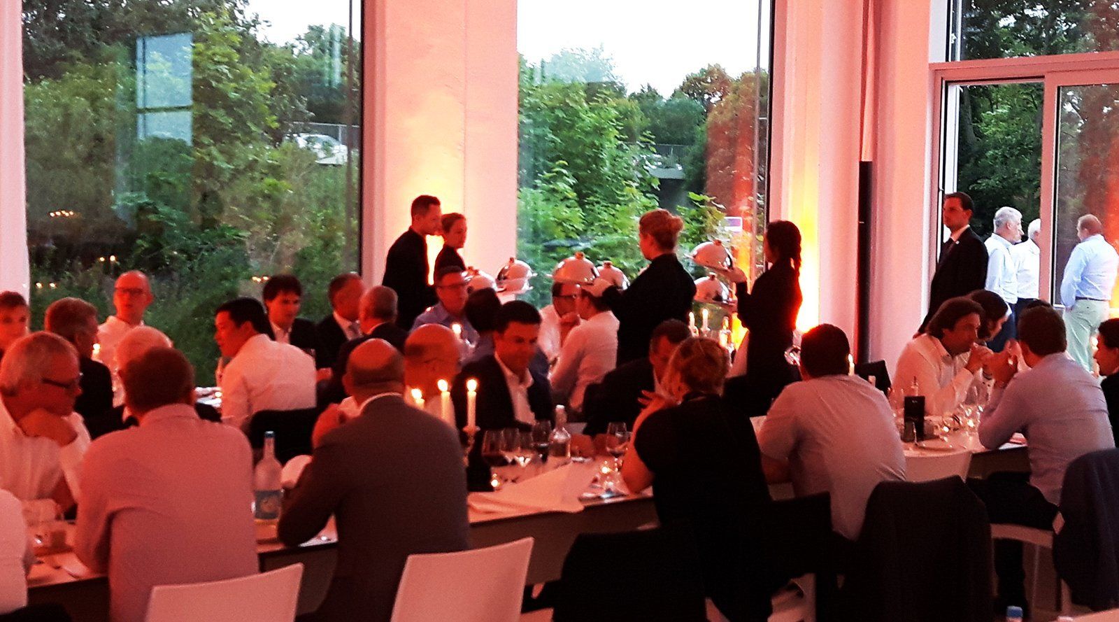 Feiernde Menschen in Studio 1, gedämpftes Licht, Mnehscn auf Terrasse im Hintergrund