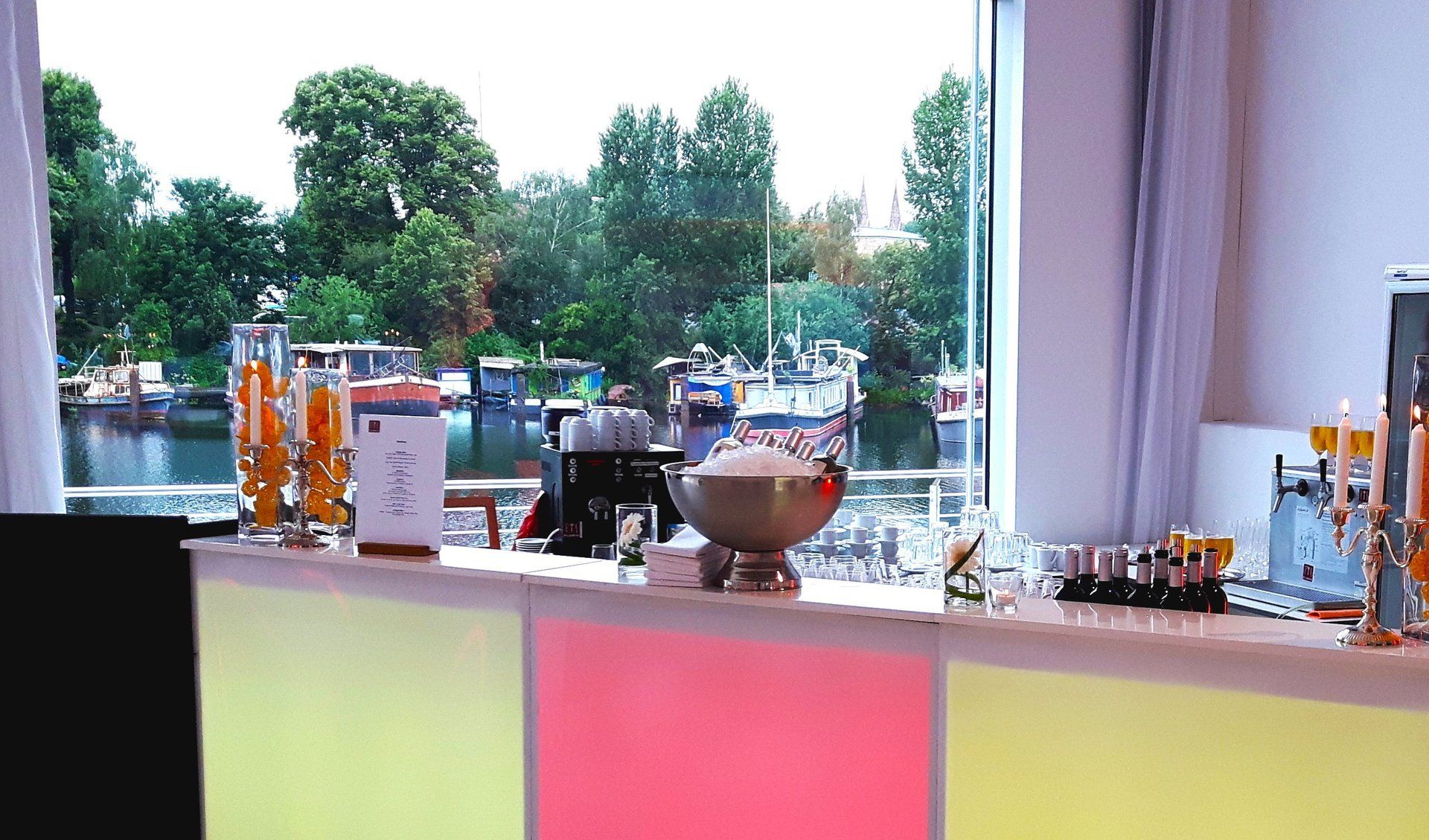 Bunt beleuchtete Bar in Studio 1. Blick auf Terrasse und Hafen