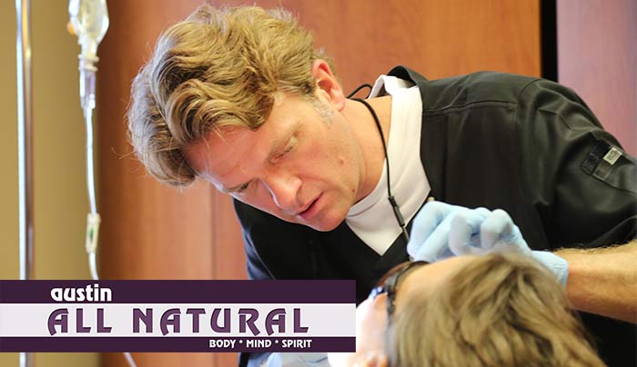 A dentist examines a child 's teeth with a sign that says all natural
