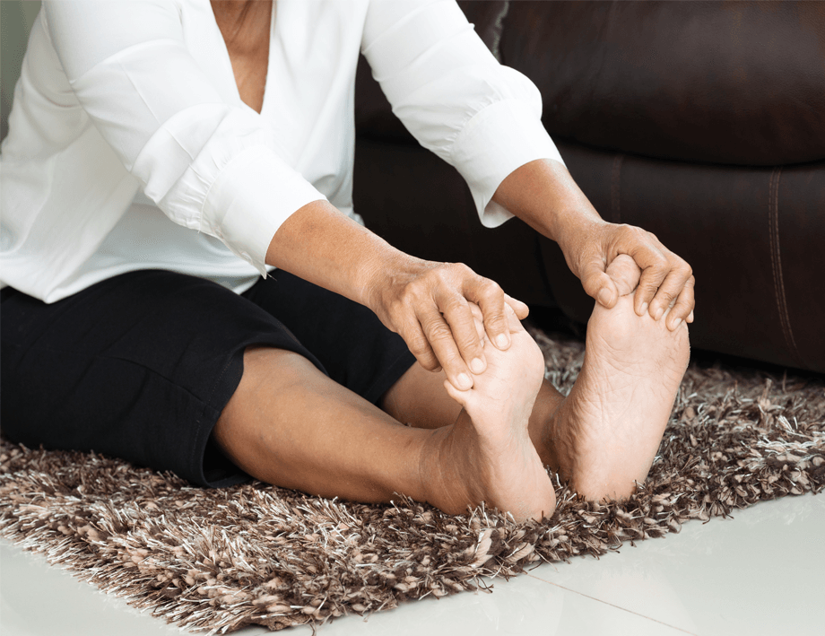 A woman is sitting on the floor stretching her feet.