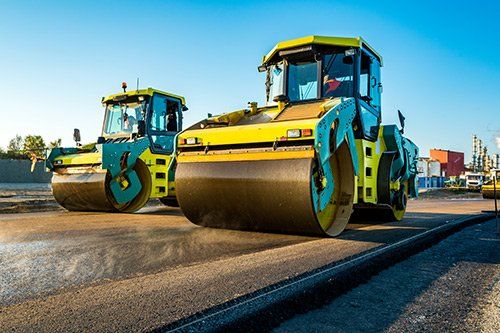 due mezzi asfaltatori di color giallo al lavoro su una strada