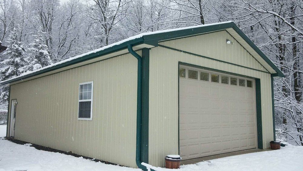 A garage with a green roof is covered in snow.