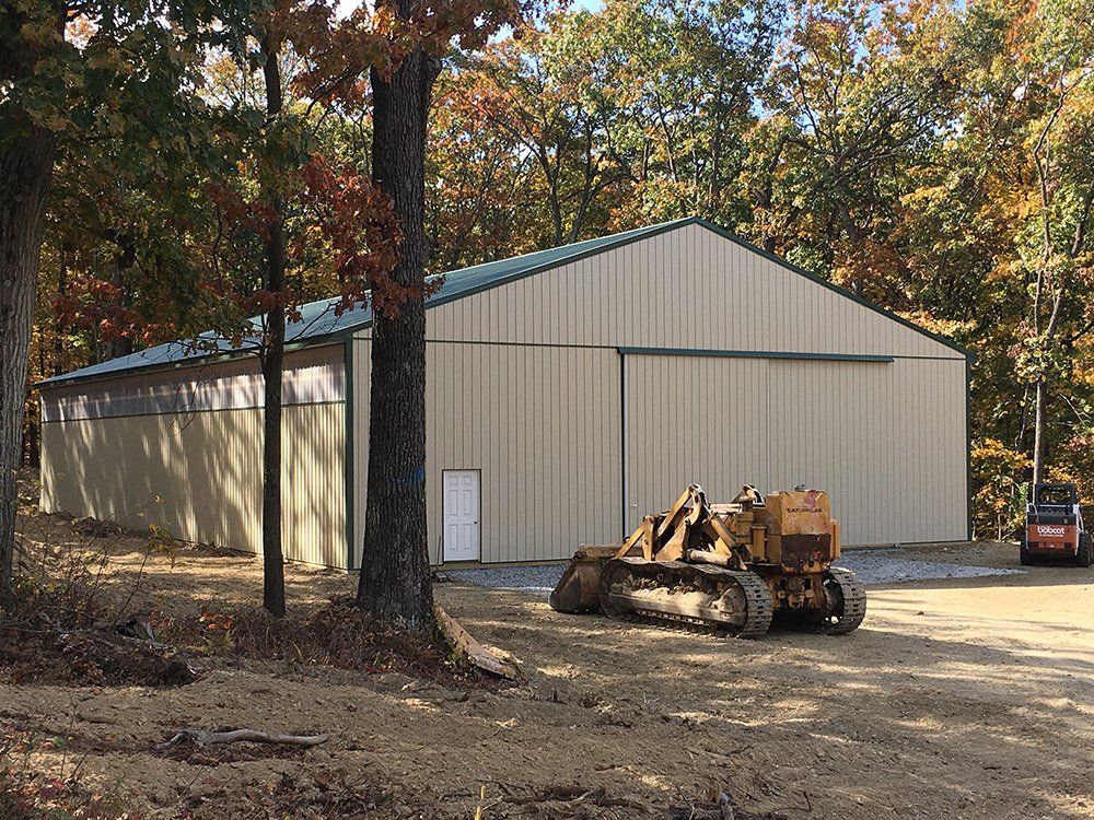 A bulldozer is parked in front of a building in the woods.