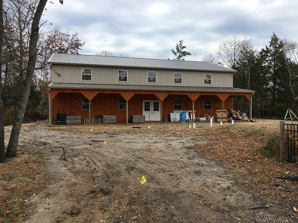 A large retail building with a porch is sitting in the middle of a dirt field.