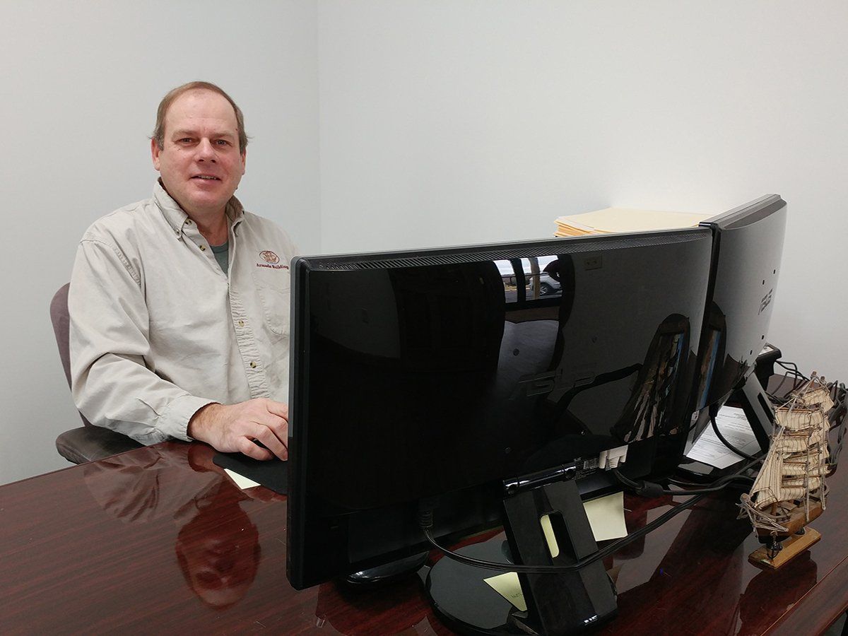 A man is sitting at a desk in front of a computer monitor