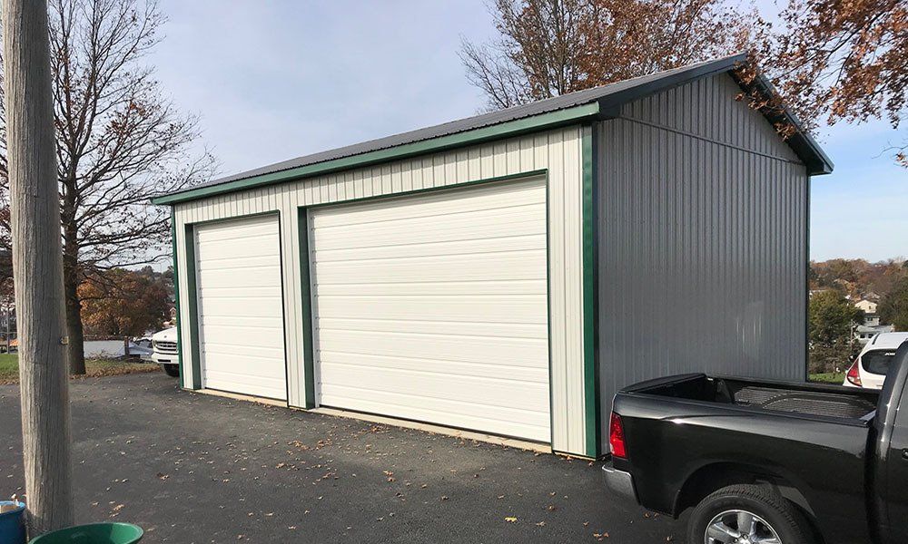 A truck is parked in front of a garage with three garage doors.