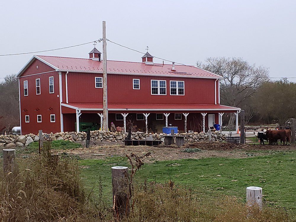A large red barn with a white roof and a porch