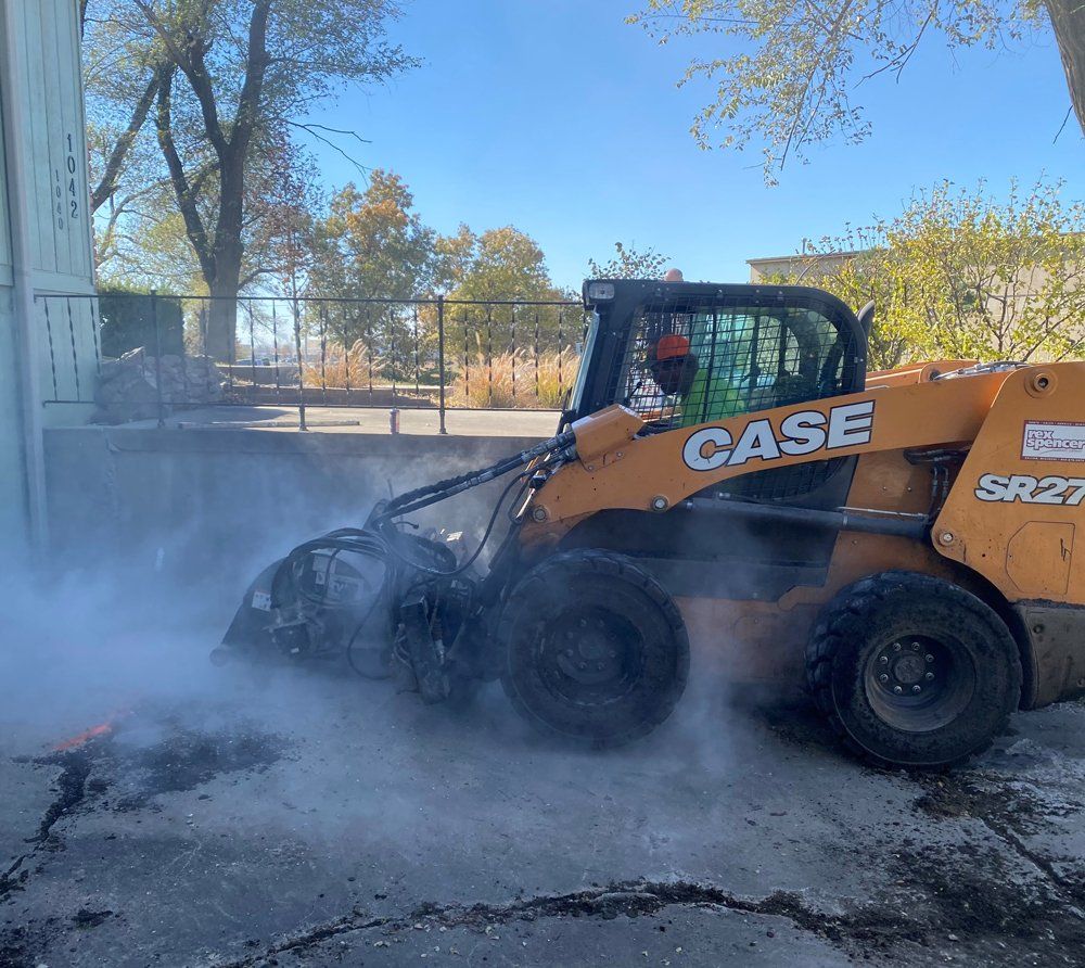 Orange CASE skid steer pushing through smoke in a lot near trees and a fence