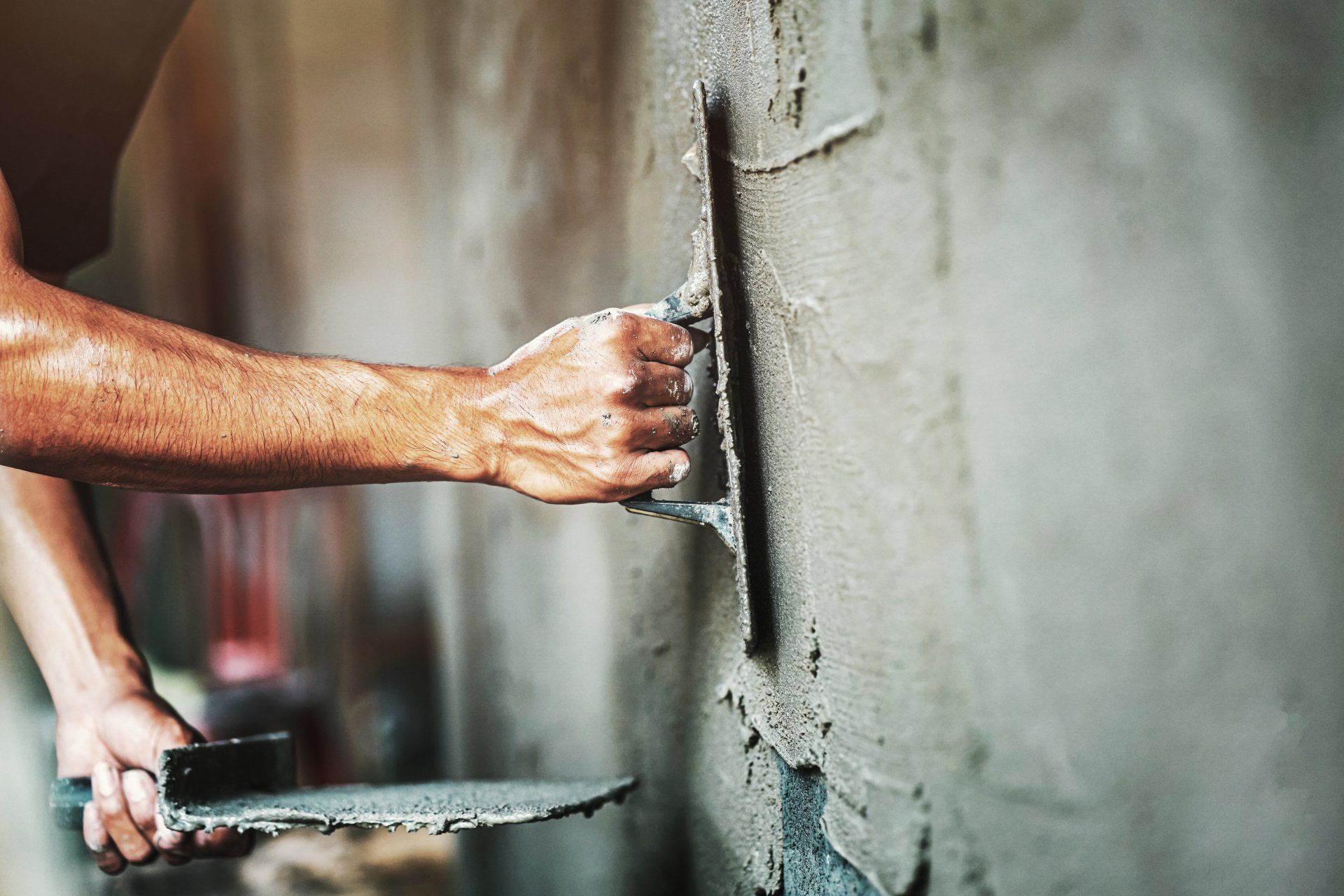A man is plastering a wall with a trowel.