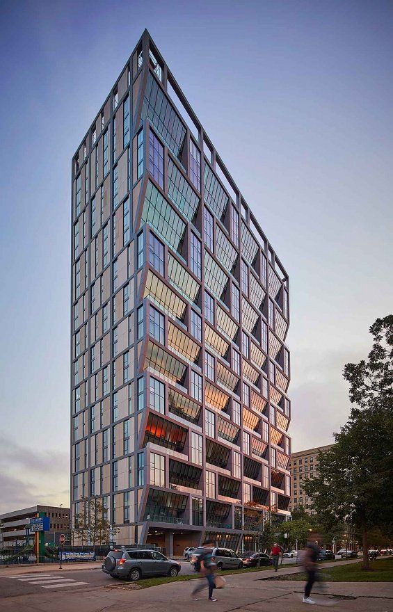 A tall building with a lot of windows and people walking in front of it.