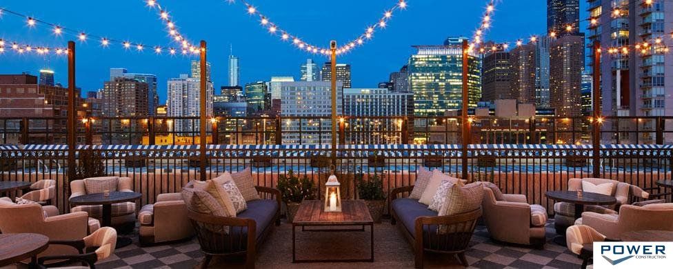 A rooftop patio with a view of the city at night.