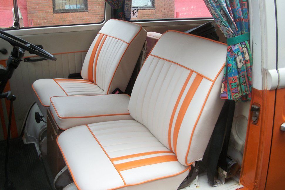 Two cream car seats which have been upholstered in cream with an orange stripe.