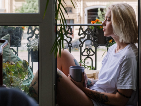 a woman is sitting on a balcony holding a cup of coffee .