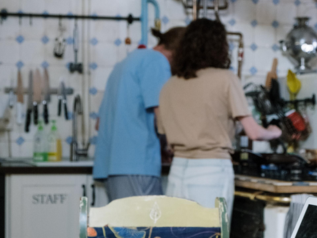 a man and woman are cooking in a kitchen with a cabinet that says staff