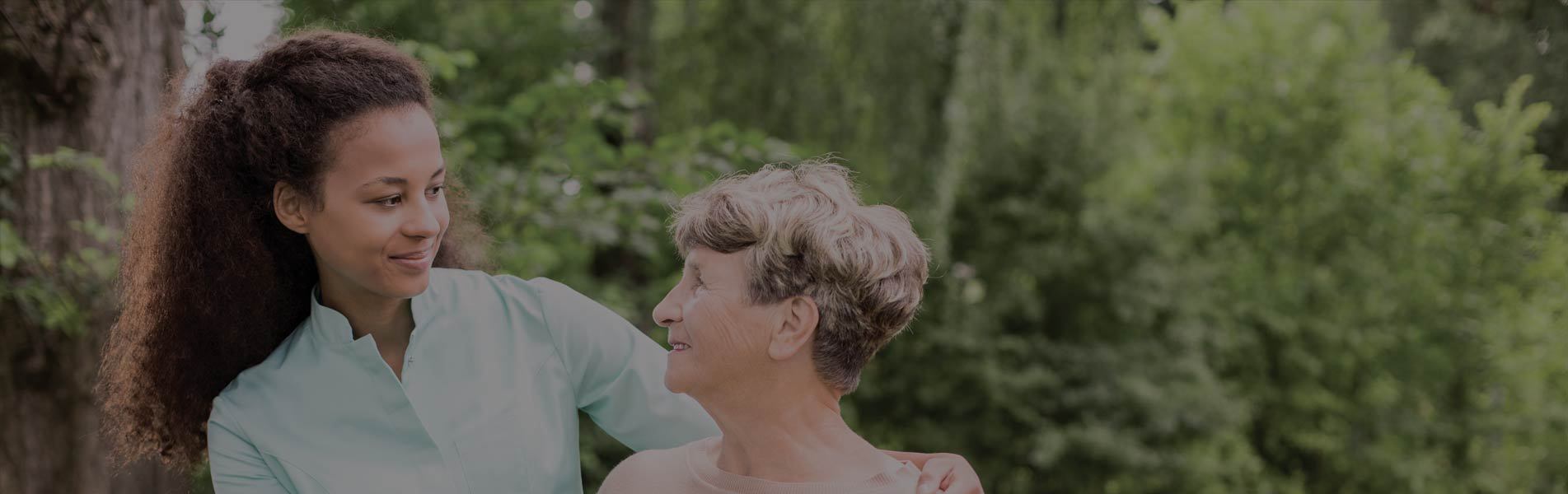 elder woman and caregiver walking in the park