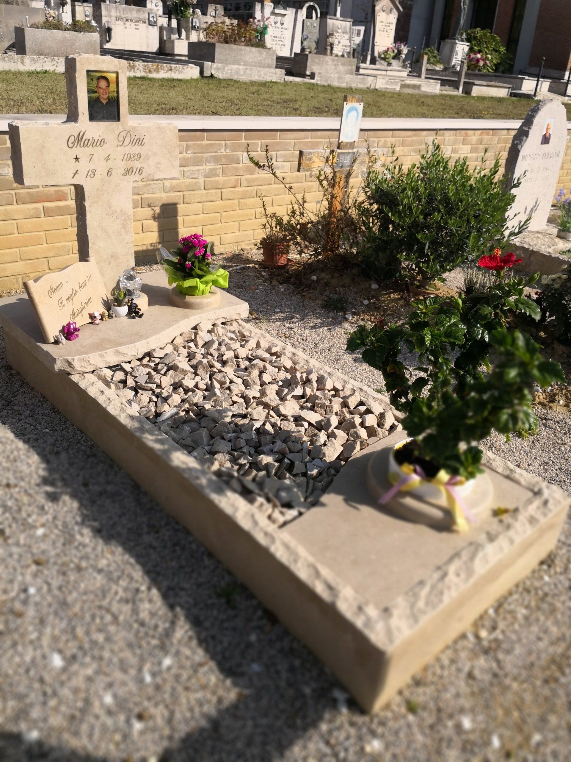 Una tomba in un cimitero con fiori e una croce