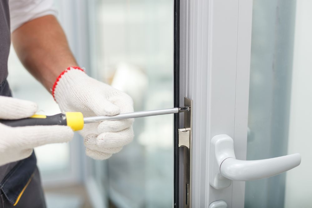an expert tightening the screws on  the lock of an aluminum door