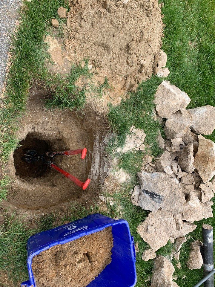 A blue bucket filled with dirt and a shovel is sitting next to a hole in the ground.