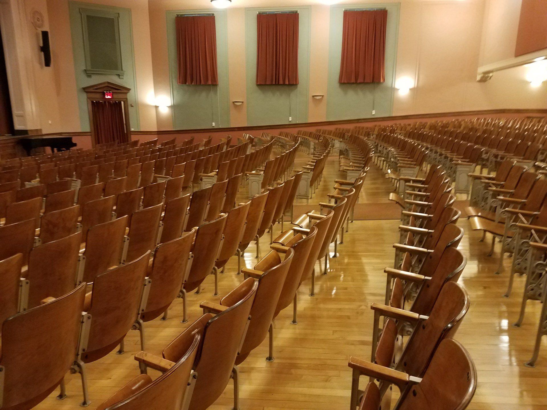 Rows of wooden chairs in a large auditorium