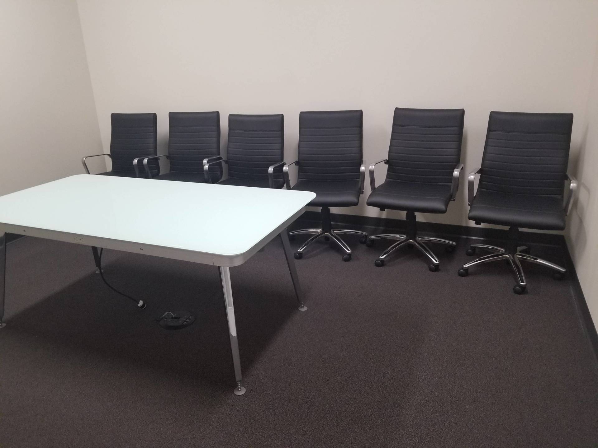 A conference room with a white table and black chairs