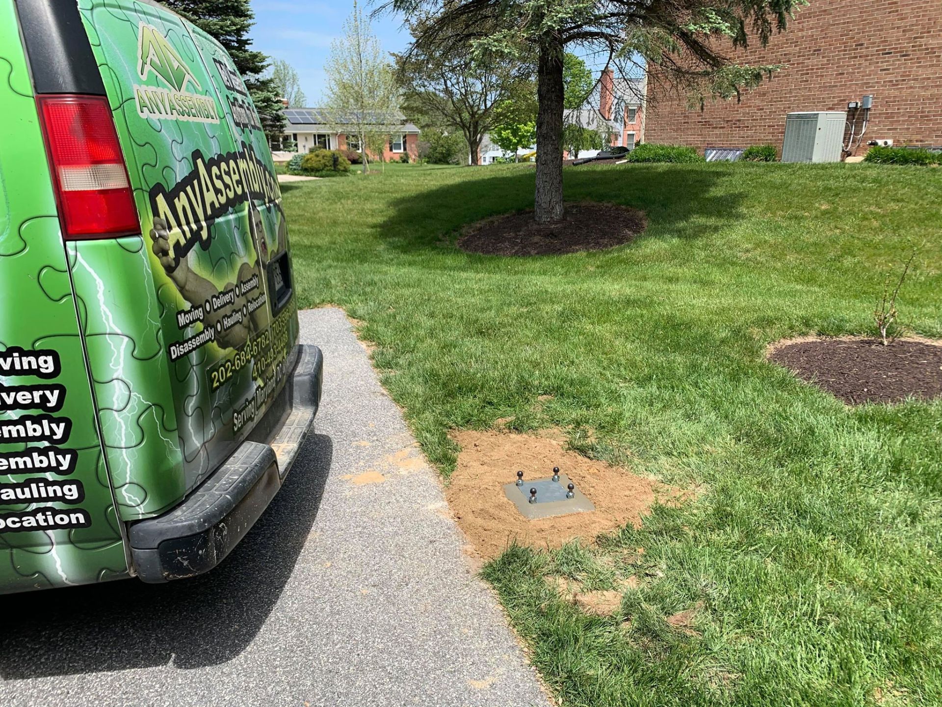 A green van is parked on the side of the road next to a tree.