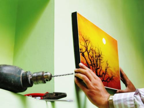 A person is hanging a picture on a wall with a drill
