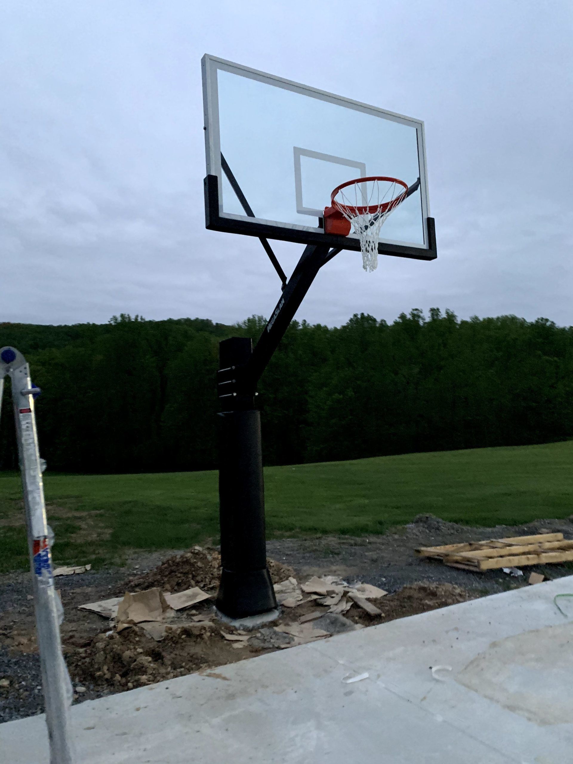 A basketball hoop is sitting on top of a concrete driveway.