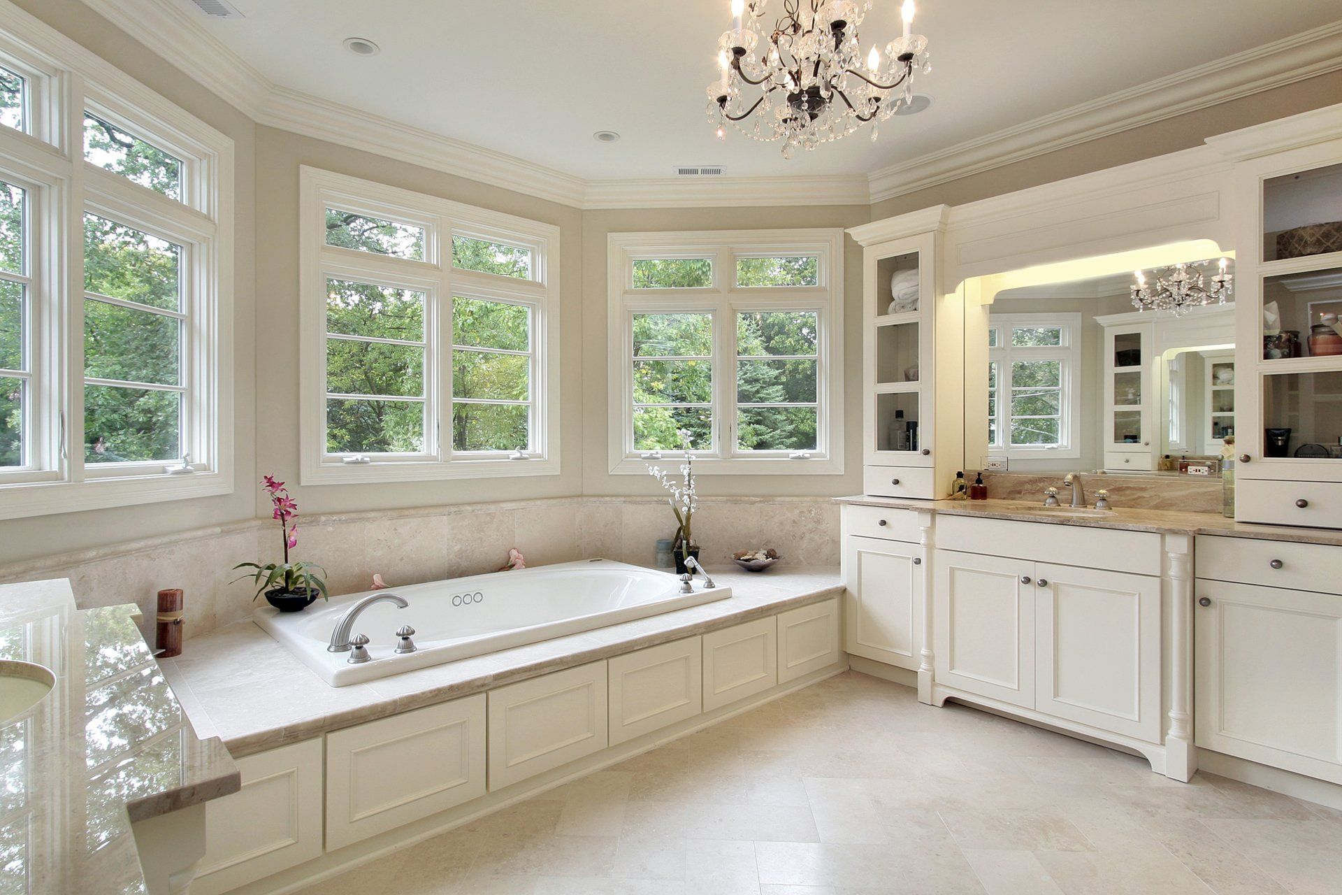 A bathroom with a tub , sink , mirror and chandelier.