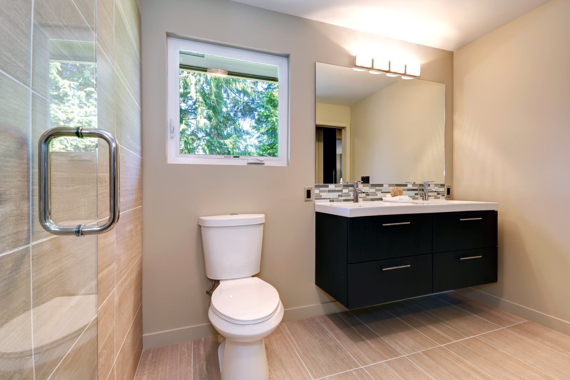 A bathroom with a toilet , sink , mirror and window.