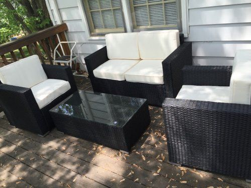 A black wicker patio set with white cushions