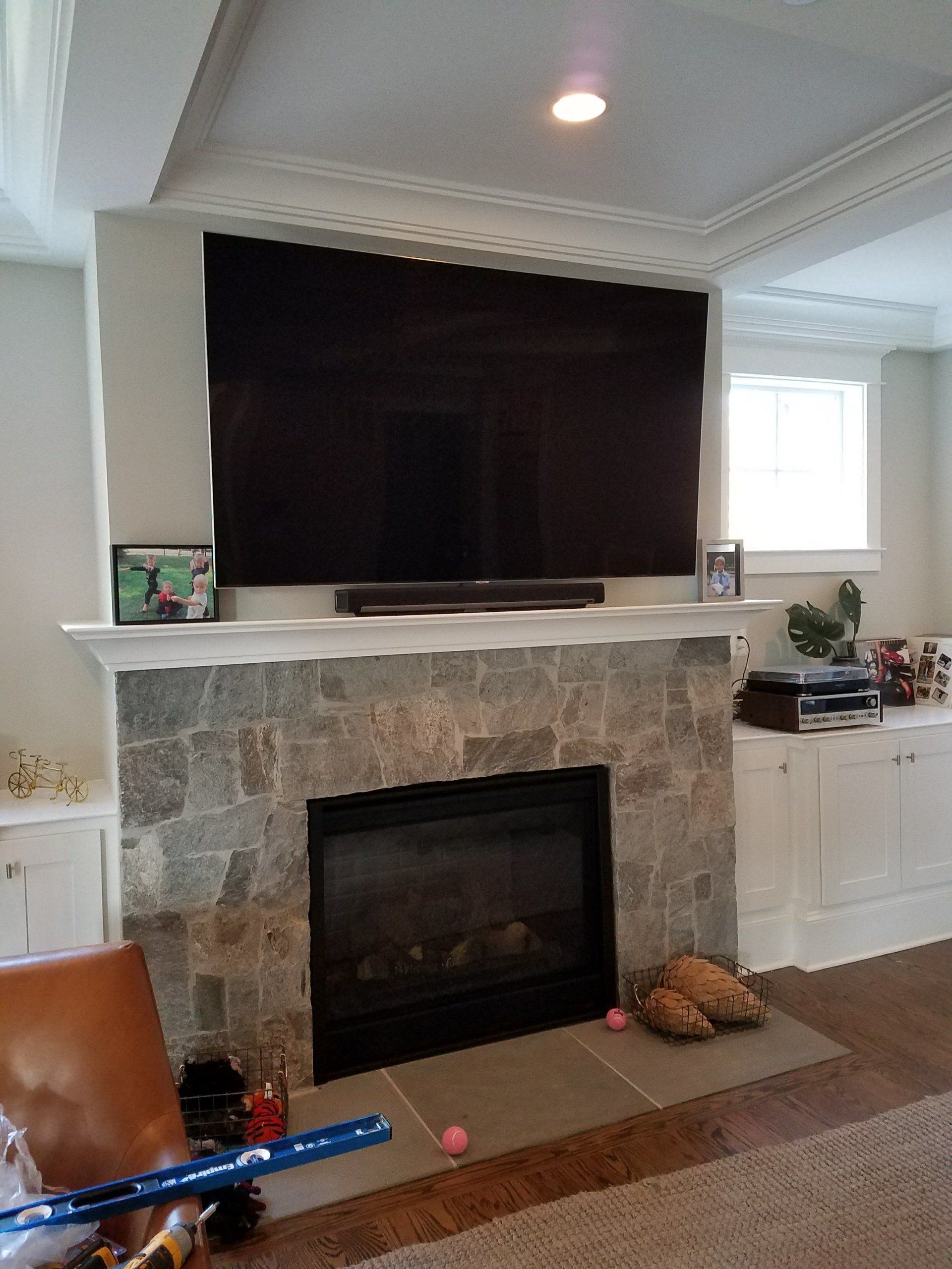 A living room with a fireplace and a flat screen tv on the wall.