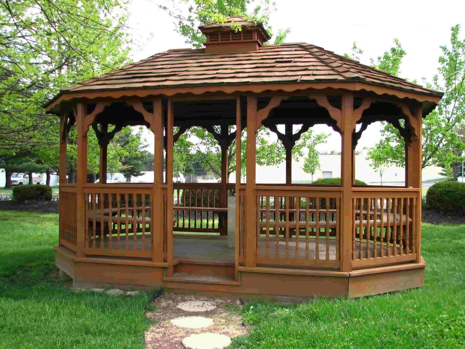 A wooden gazebo is sitting in the middle of a lush green field.