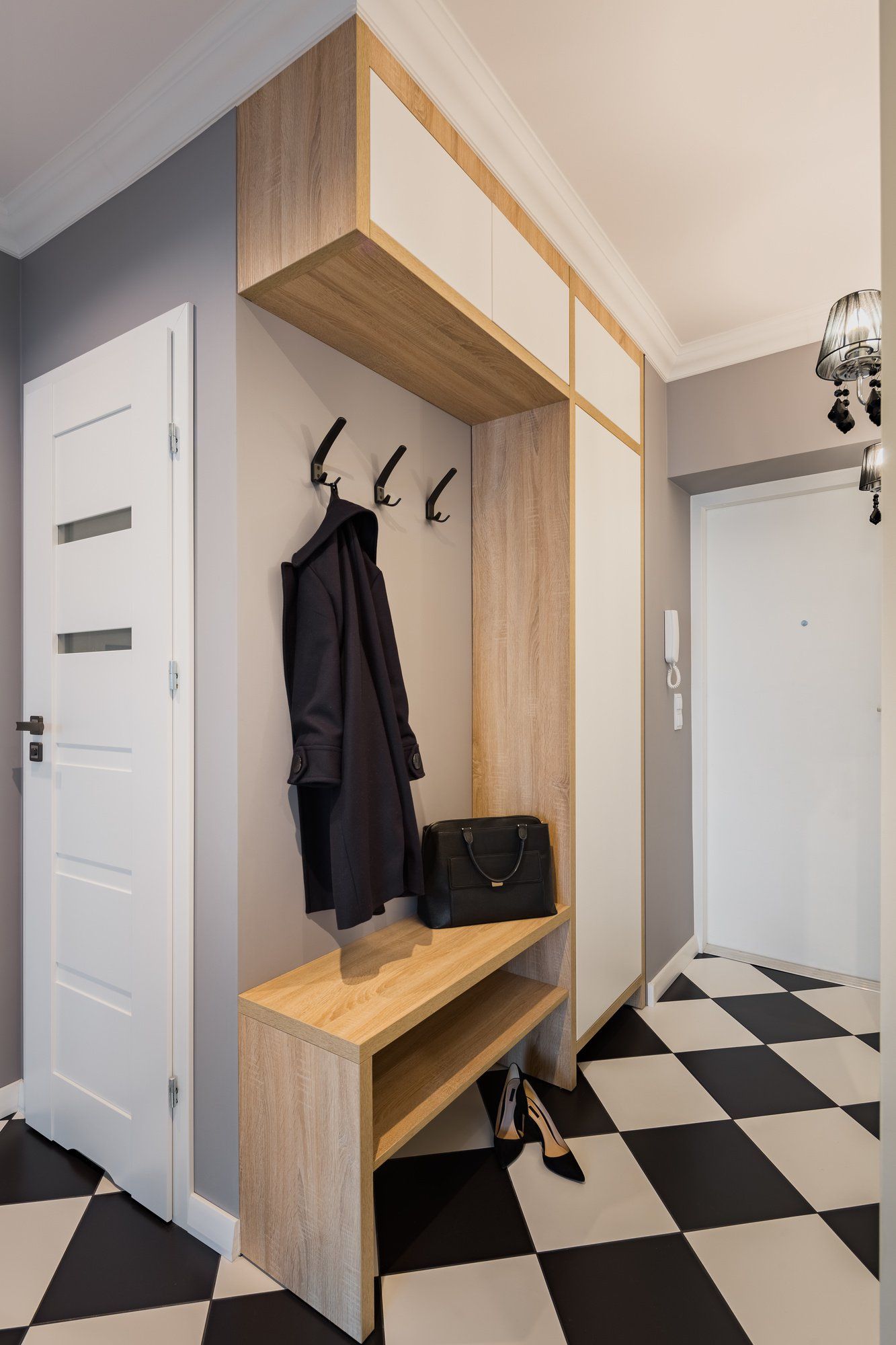 A hallway with a coat rack and a checkered floor.
