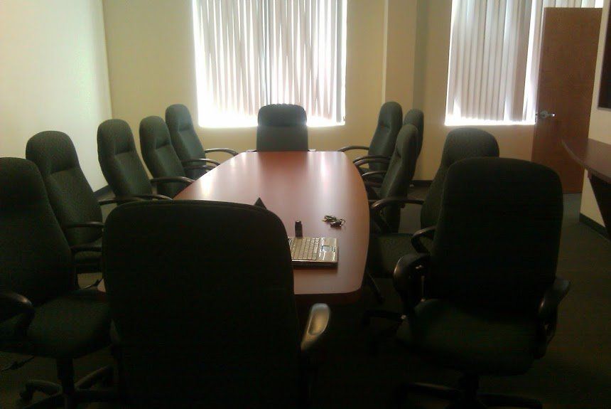 A conference room with a long table and black chairs