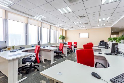 A large empty office with lots of desks and chairs.