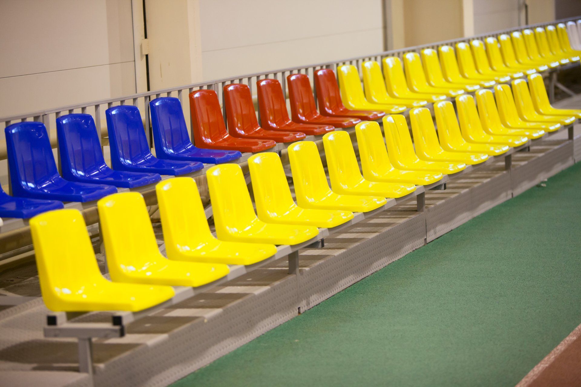 A row of yellow , red and blue plastic seats in a stadium