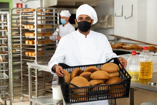 Man holding loaves of bread in a food factory in Mississauga, Ontario.