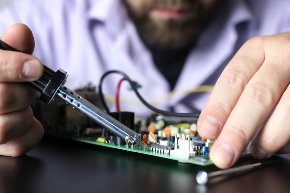 tecnico in sede mentre ripara una scheda elettronica