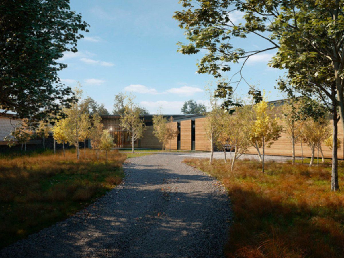 Gravel path leading to a modern brick building with trees and autumn foliage