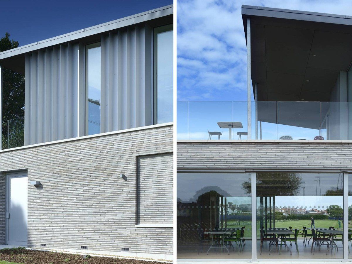Modern two-story house with large glass windows and a covered patio under a blue sky