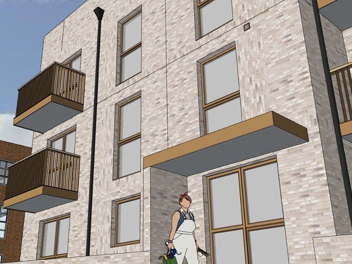 Apartment building exterior with balconies and a person standing by the entrance
