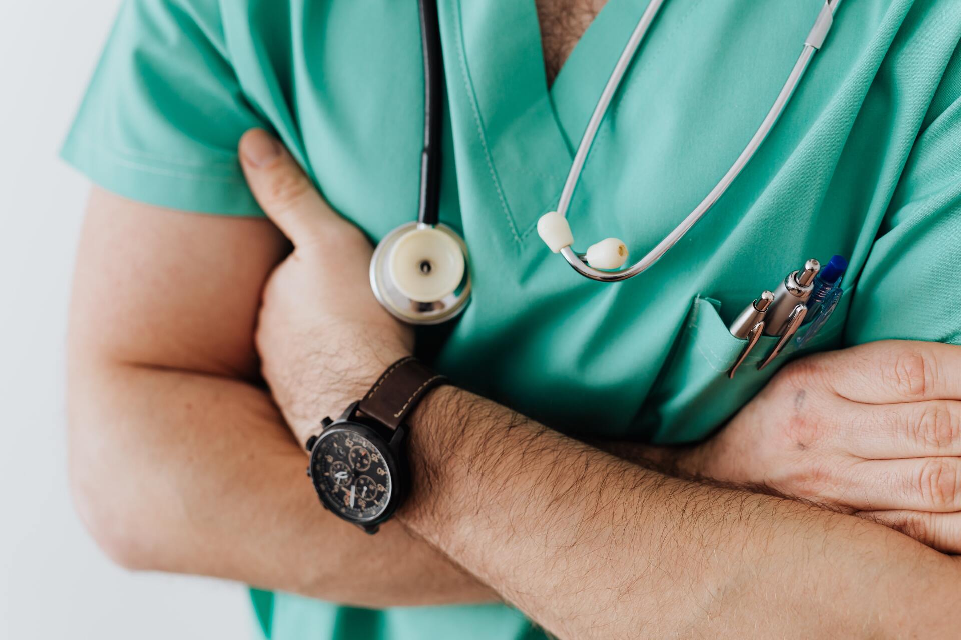 Health practitioner in green scrubs with arms crossed