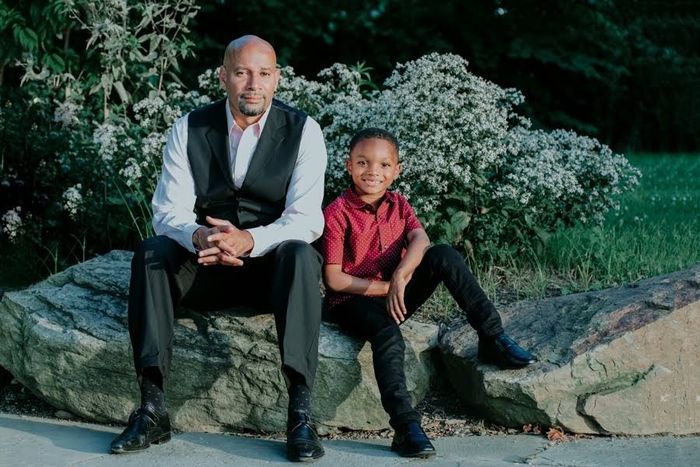 A man and a boy are sitting on a rock.
