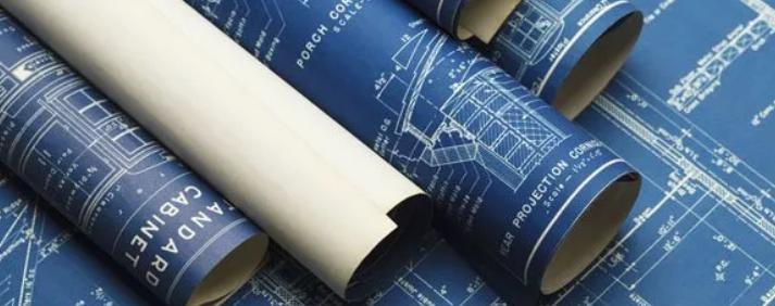 Blueprints and rolled architectural plans stacked together